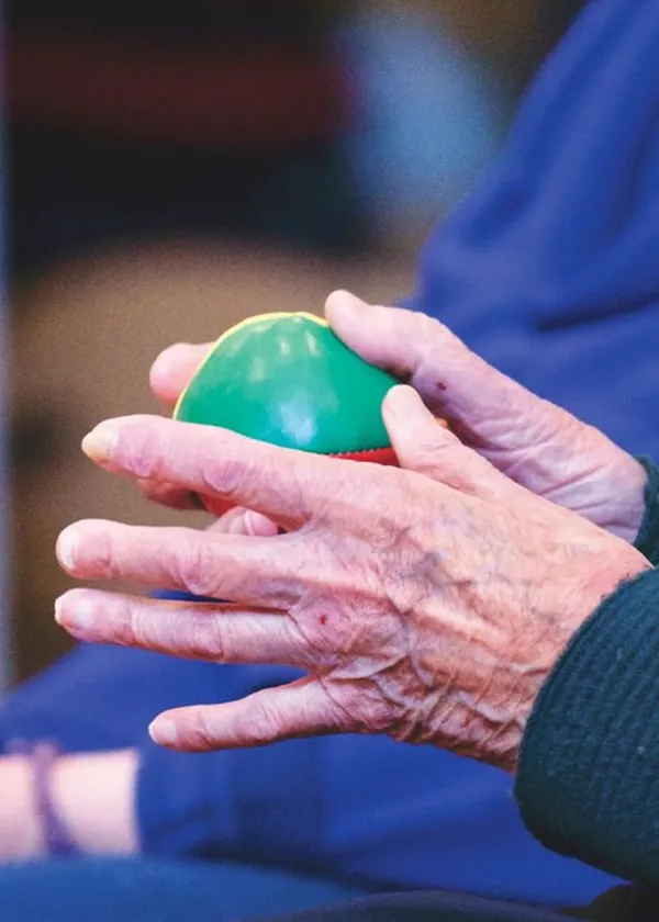 Manos de una persona mayor ejercitando con una pelota de terapia